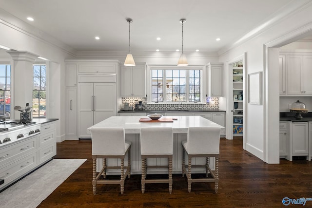 kitchen featuring a kitchen breakfast bar, dark wood-style floors, and ornamental molding