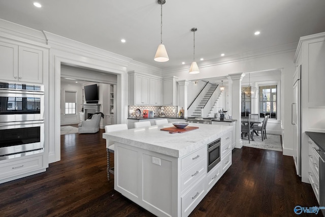 kitchen featuring white cabinets, stainless steel appliances, crown molding, and dark wood-type flooring