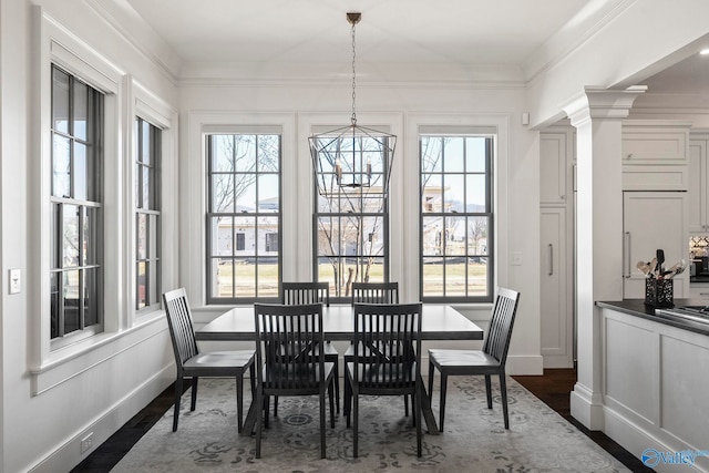 dining area with decorative columns, baseboards, dark wood-style floors, and ornamental molding