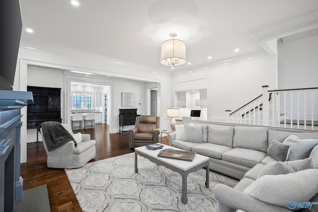 living area with wood finished floors, stairway, a fireplace, and crown molding