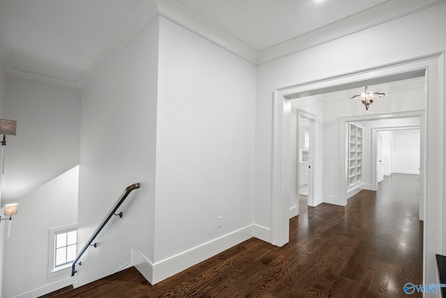 hall with an upstairs landing, wood finished floors, an inviting chandelier, crown molding, and baseboards