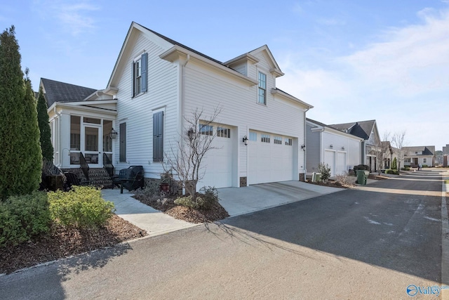 view of home's exterior with driveway, an attached garage, and a sunroom