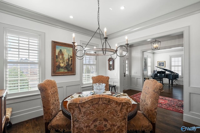 dining space featuring a notable chandelier, wood finished floors, a decorative wall, and ornamental molding