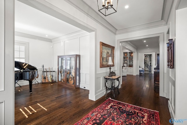 hallway featuring a decorative wall, wood finished floors, and ornamental molding