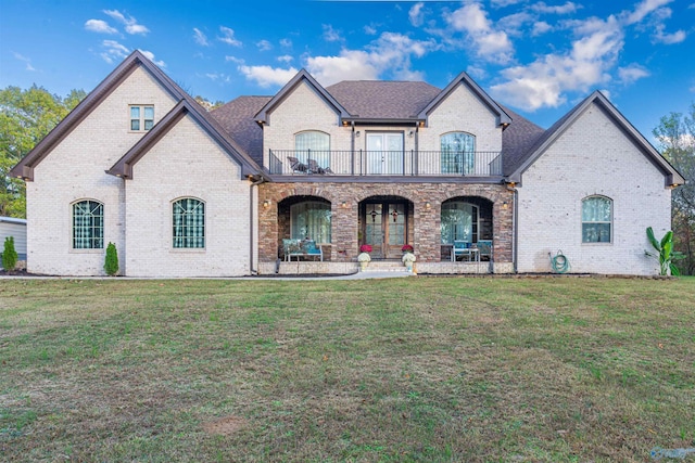 french provincial home with a front yard, a balcony, and covered porch