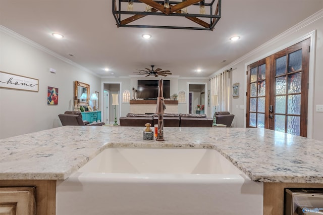 kitchen with sink, ornamental molding, light stone countertops, and french doors