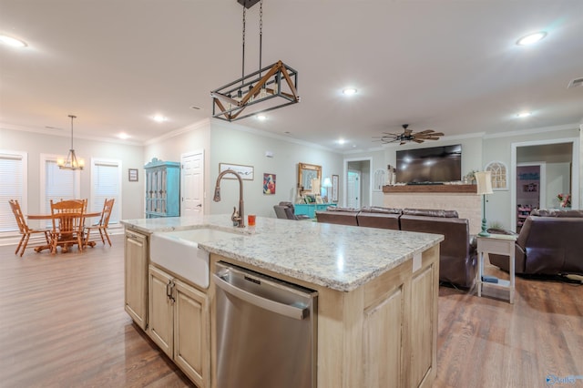 kitchen with pendant lighting, an island with sink, sink, stainless steel dishwasher, and light stone countertops