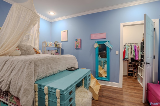 bedroom featuring crown molding, a spacious closet, a closet, and hardwood / wood-style flooring