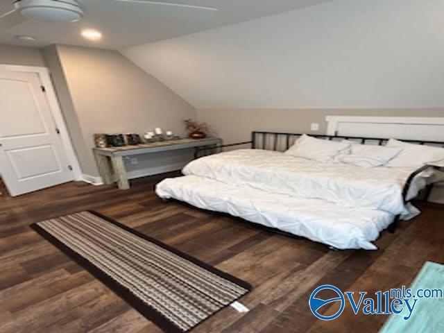 bedroom with vaulted ceiling and dark hardwood / wood-style flooring