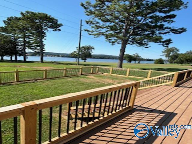 wooden terrace featuring a water view and a lawn