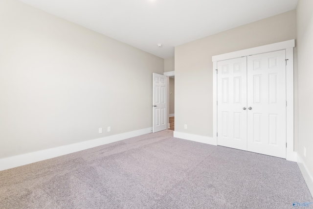 unfurnished bedroom with a closet, carpet flooring, and baseboards