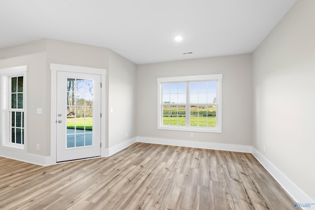 entryway with baseboards, light wood-type flooring, visible vents, and a healthy amount of sunlight