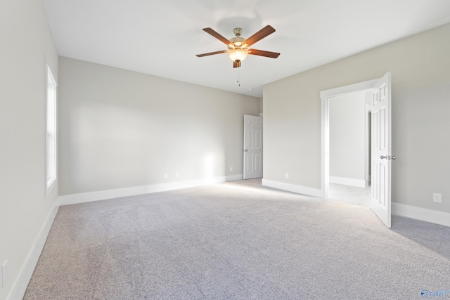 spare room featuring a wealth of natural light, a ceiling fan, baseboards, and light carpet