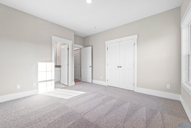 unfurnished bedroom featuring a closet, baseboards, and light carpet