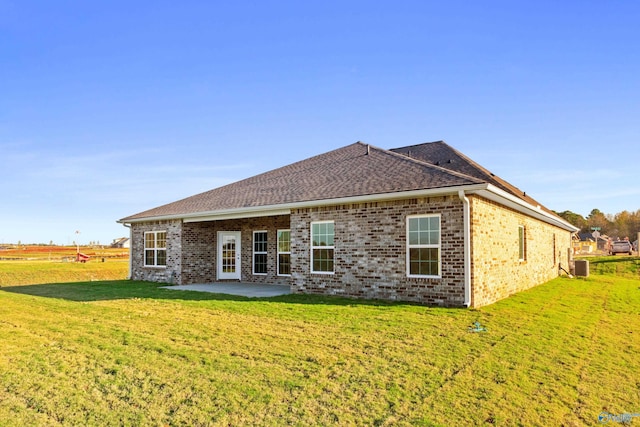 rear view of house featuring a lawn, central AC, a patio, and brick siding