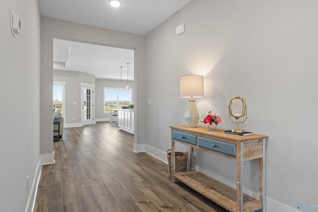 corridor with dark wood-style flooring and baseboards