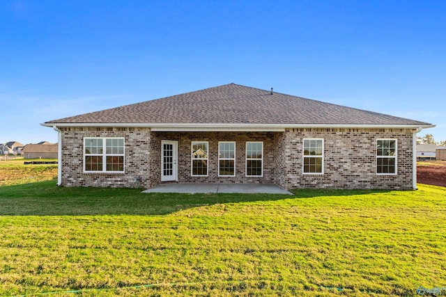back of house featuring a patio, roof with shingles, a yard, and brick siding