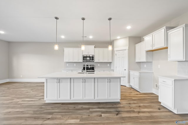 kitchen with decorative backsplash, white cabinets, appliances with stainless steel finishes, light countertops, and light wood-type flooring