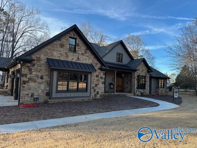 view of front of property with metal roof, stone siding, a standing seam roof, and a front yard