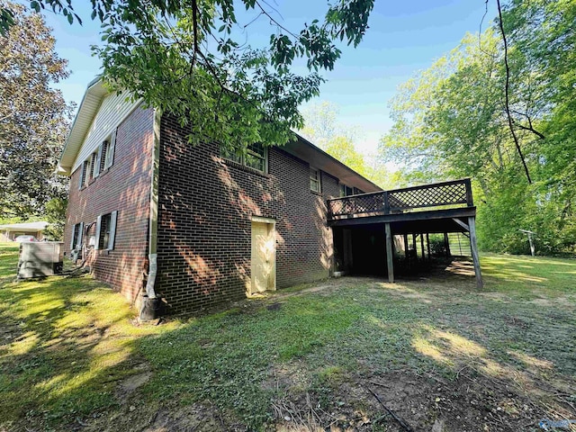 rear view of house featuring brick siding, a lawn, and a wooden deck