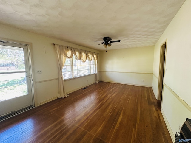 spare room with baseboards, a ceiling fan, wood finished floors, and visible vents