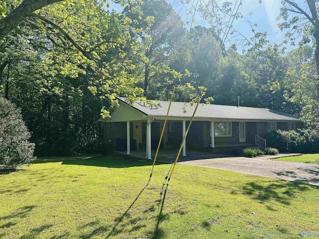 view of front of house featuring driveway, metal roof, a carport, and a front lawn