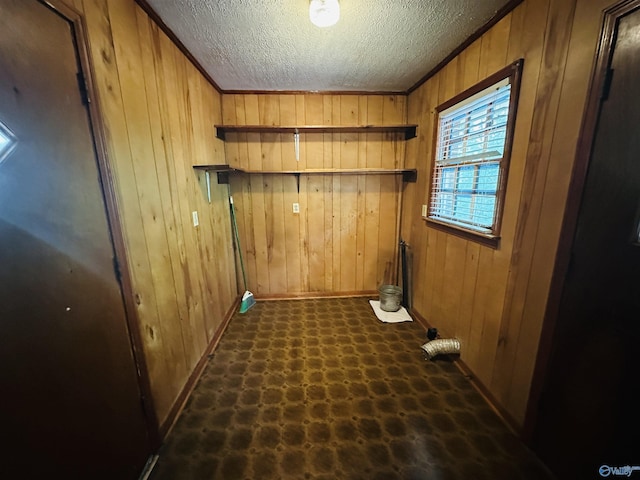 washroom featuring laundry area, a textured ceiling, wood walls, dark floors, and baseboards