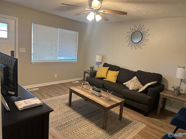 living room with ceiling fan, light hardwood / wood-style floors, and a textured ceiling