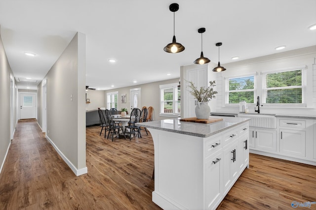 2605 Ready Section Rd, Toney, AL 35773 - kitchen featuring a kitchen island, wood finished floors, white cabinets, light stone counters, and hanging light fixtures