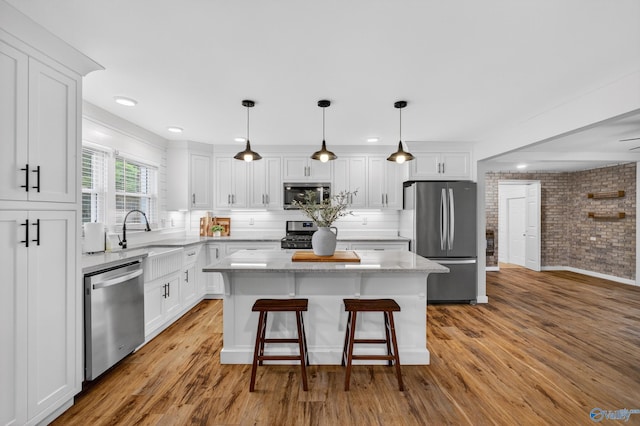 2605 Ready Section Rd, Toney, AL 35773 - kitchen featuring stainless steel appliances, white cabinets, a center island, light wood finished floors, and a kitchen bar