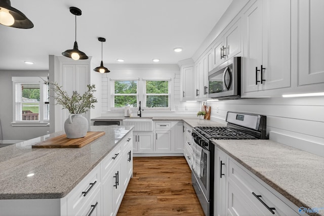 2605 Ready Section Rd, Toney, AL 35773 - kitchen featuring appliances with stainless steel finishes, white cabinets, wood finished floors, a center island, and light stone countertops