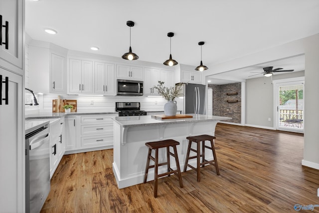 2605 Ready Section Rd, Toney, AL 35773 - kitchen featuring appliances with stainless steel finishes, light wood-type flooring, white cabinetry, a kitchen island, and a kitchen breakfast bar