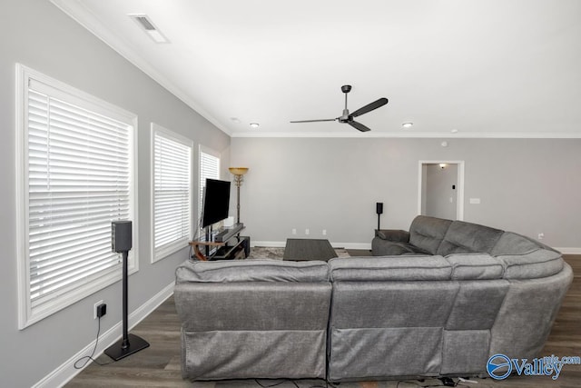 living area with baseboards, wood finished floors, visible vents, and crown molding