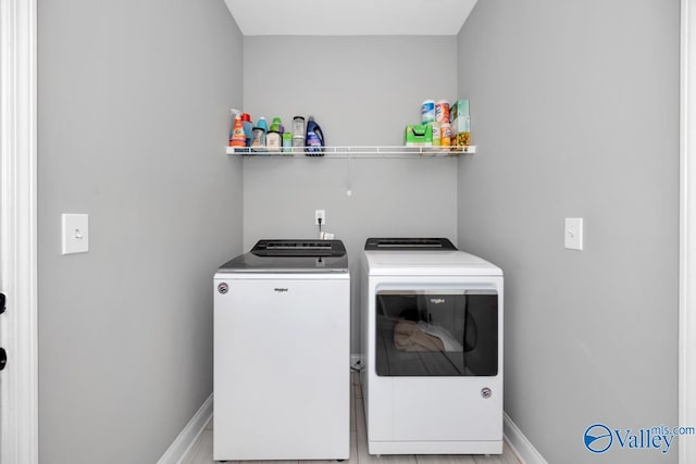 washroom featuring laundry area, baseboards, and washer and dryer