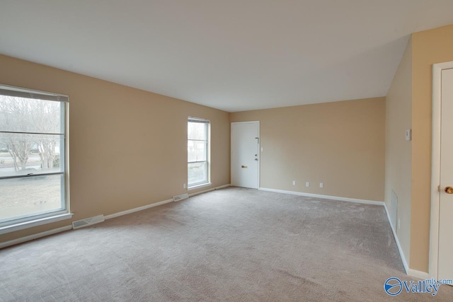 spare room featuring carpet flooring, visible vents, and baseboards