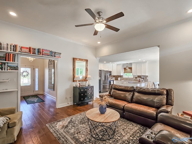 living room with dark wood-type flooring, ceiling fan, ornamental molding, and sink