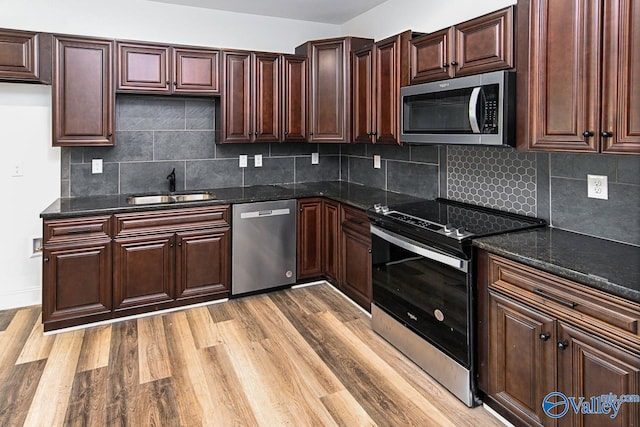 kitchen featuring appliances with stainless steel finishes, light wood-type flooring, backsplash, and sink