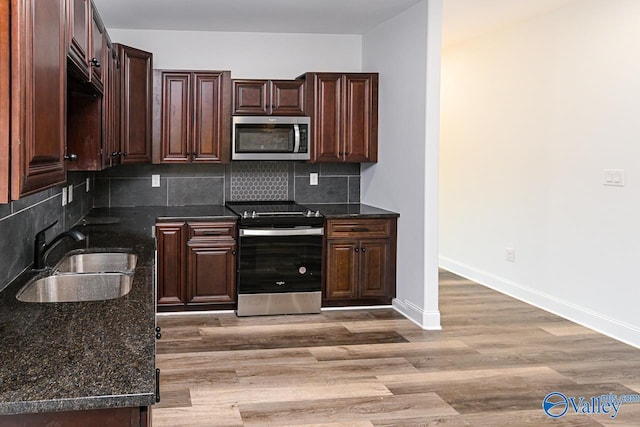 kitchen with hardwood / wood-style floors, backsplash, stainless steel appliances, and sink