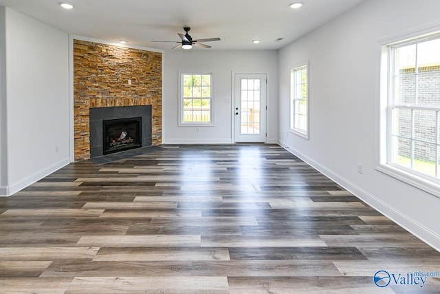 unfurnished living room with dark hardwood / wood-style flooring, a healthy amount of sunlight, and a tiled fireplace