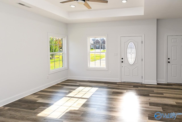 entryway with ceiling fan, dark wood-type flooring, and a tray ceiling