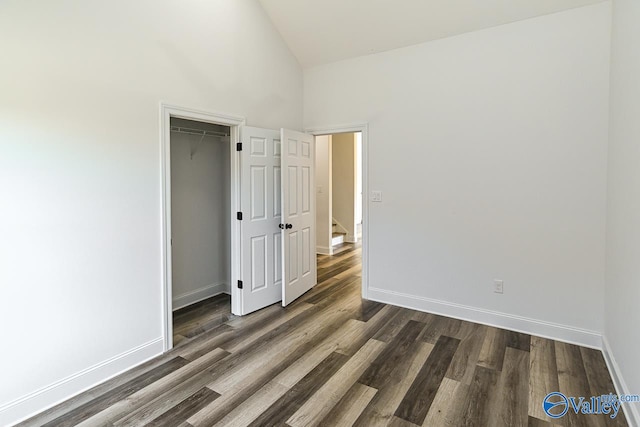 unfurnished bedroom featuring a closet, dark wood-type flooring, and a high ceiling