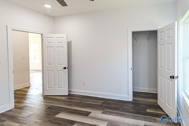 unfurnished bedroom featuring dark hardwood / wood-style flooring, a closet, multiple windows, and ceiling fan