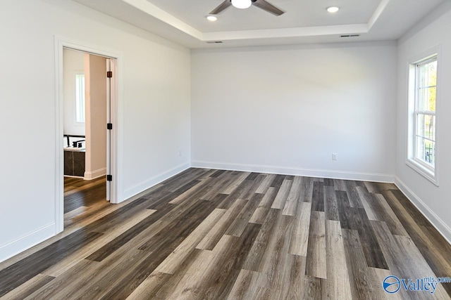 empty room featuring dark hardwood / wood-style floors, a raised ceiling, and ceiling fan