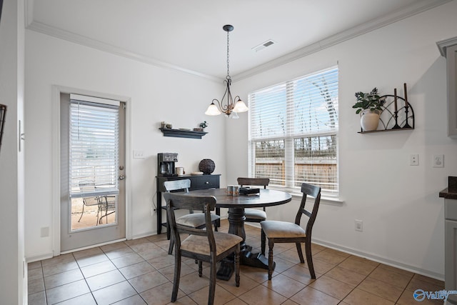 tiled dining space featuring crown molding and a chandelier