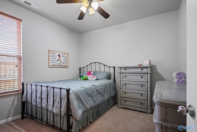 bedroom featuring multiple windows, light colored carpet, and ceiling fan