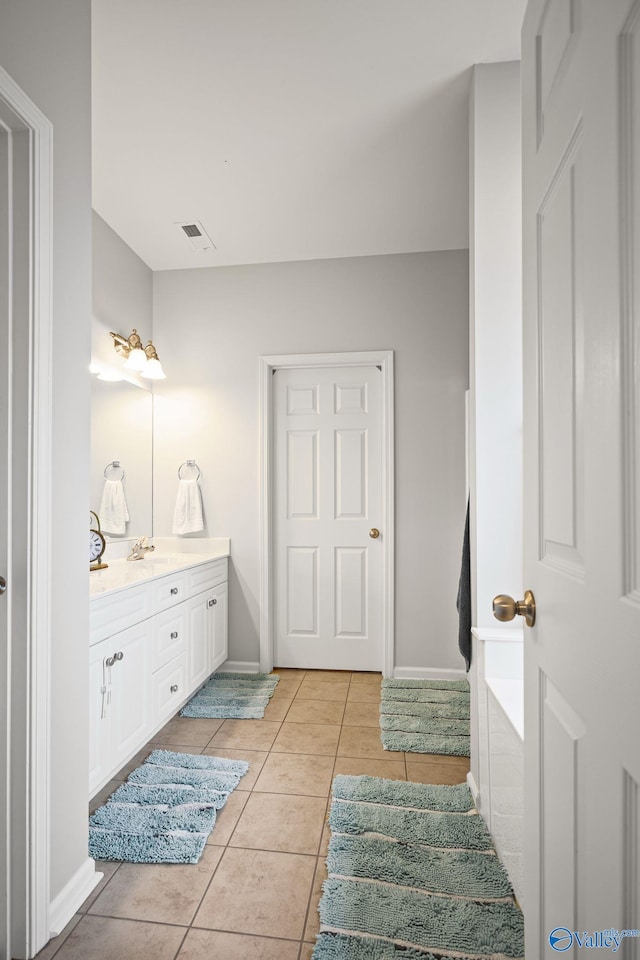 bathroom featuring tile patterned flooring, vanity, and a bath