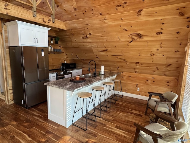 kitchen with white cabinets, stainless steel appliances, dark stone countertops, sink, and dark hardwood / wood-style floors