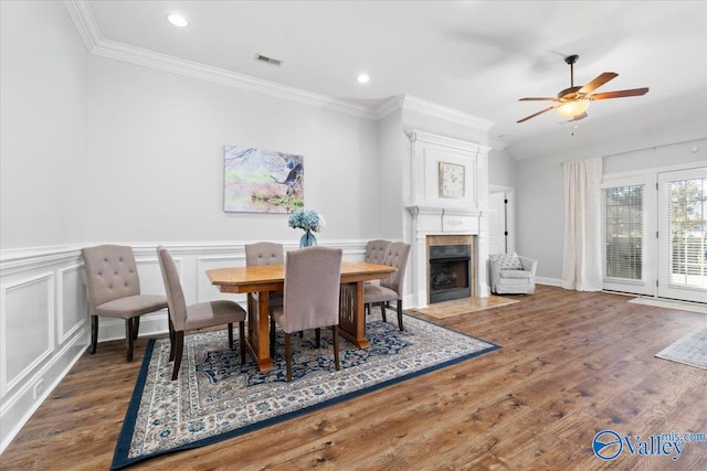 dining space featuring ceiling fan, dark hardwood / wood-style flooring, ornamental molding, and a fireplace