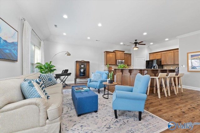 living room featuring ceiling fan, light wood-type flooring, and ornamental molding