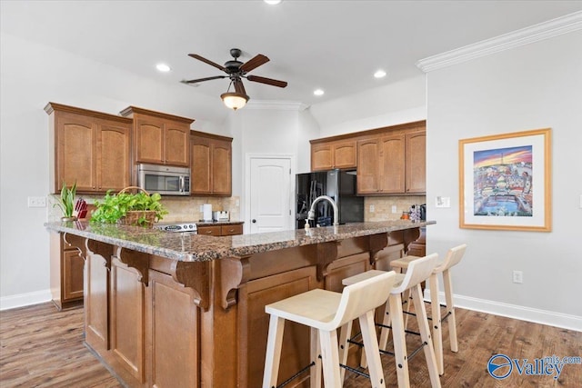 kitchen with dark stone counters, black fridge, backsplash, and a breakfast bar area